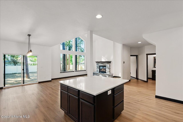 kitchen featuring a fireplace, baseboards, open floor plan, light wood-style floors, and light countertops