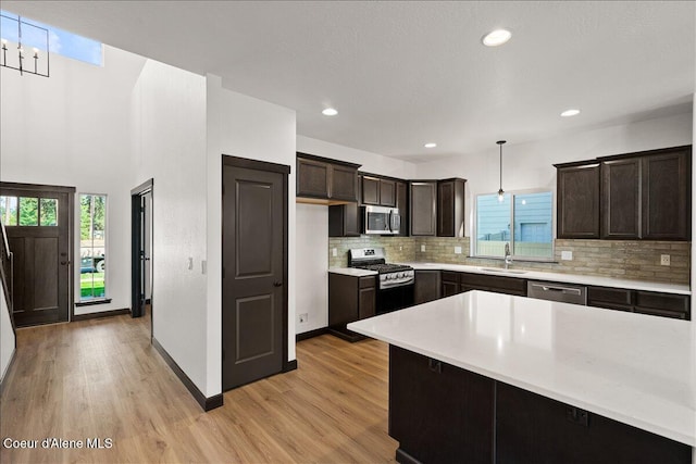 kitchen with dark brown cabinetry, a sink, light wood finished floors, light countertops, and stainless steel appliances