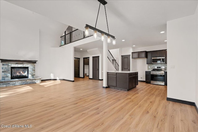 kitchen with appliances with stainless steel finishes, light wood-type flooring, light countertops, open floor plan, and recessed lighting