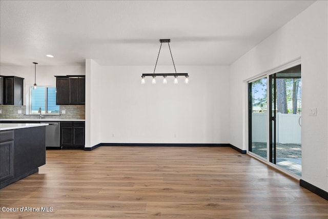 interior space with light countertops, decorative backsplash, a healthy amount of sunlight, and dishwasher