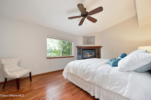 8533 N Tartan Dr, Hayden, ID 83835 - bedroom with vaulted ceiling, wood finished floors, baseboards, a glass covered fireplace, and a ceiling fan