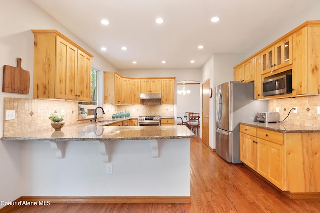 8533 N Tartan Dr, Hayden, ID 83835 - kitchen with stainless steel appliances, a sink, a peninsula, under cabinet range hood, and light brown cabinetry