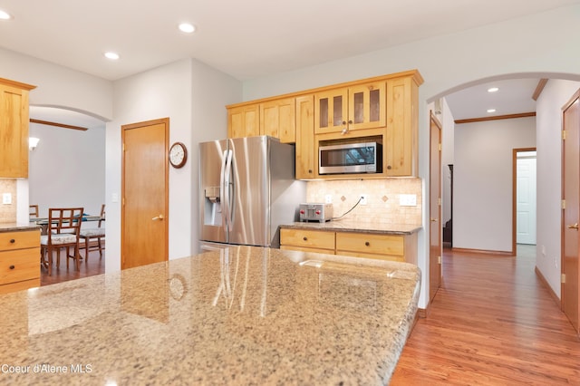 8533 N Tartan Dr, Hayden, ID 83835 - kitchen with appliances with stainless steel finishes, arched walkways, light wood-type flooring, backsplash, and recessed lighting