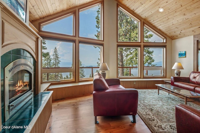 living area with a tiled fireplace, wood ceiling, high vaulted ceiling, and hardwood / wood-style flooring