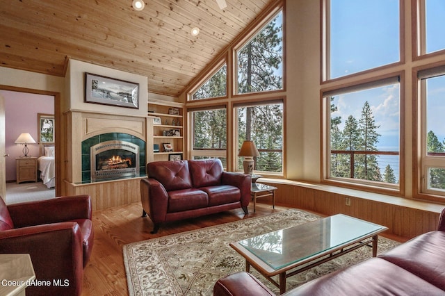 living area featuring wood walls, wood finished floors, a tile fireplace, wooden ceiling, and high vaulted ceiling