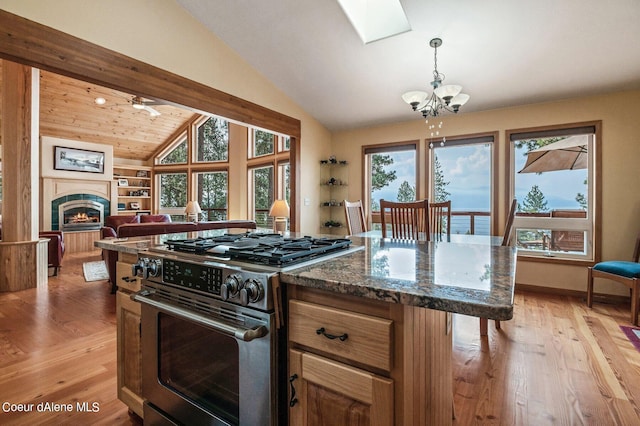 kitchen featuring an inviting chandelier, open floor plan, lofted ceiling with skylight, gas range, and light wood-style flooring