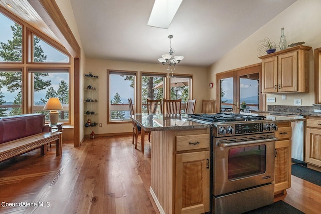 kitchen with vaulted ceiling with skylight, light wood-style flooring, a chandelier, and gas stove