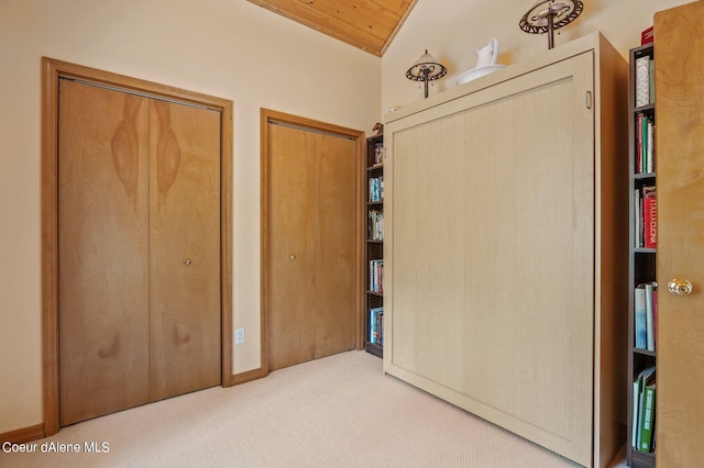 unfurnished bedroom with multiple closets, lofted ceiling, wood ceiling, and carpet