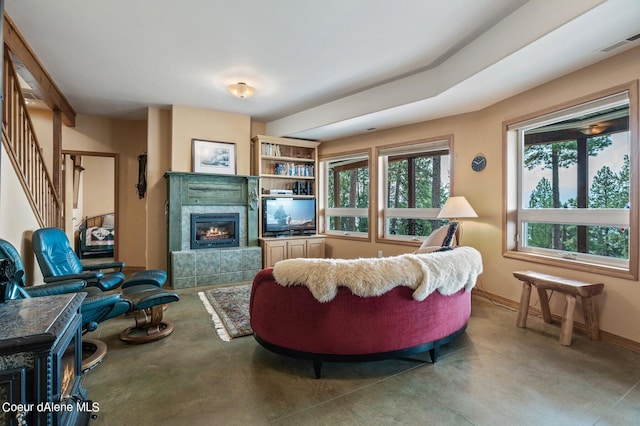 living room featuring a tiled fireplace, concrete floors, stairs, baseboards, and visible vents