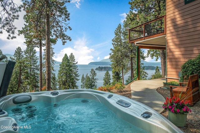 view of swimming pool with a water and mountain view and a hot tub