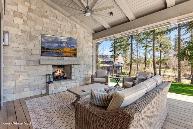 wooden terrace featuring ceiling fan and an outdoor stone fireplace