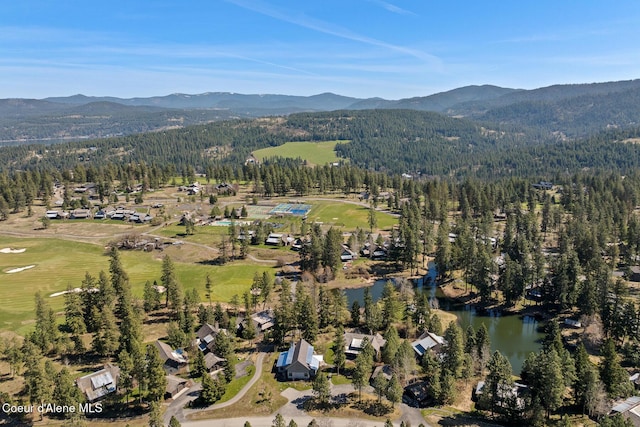 drone / aerial view featuring a view of trees, a water and mountain view, and golf course view