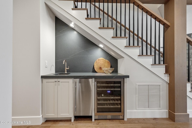 bar with visible vents, wine cooler, fridge, indoor wet bar, and a sink
