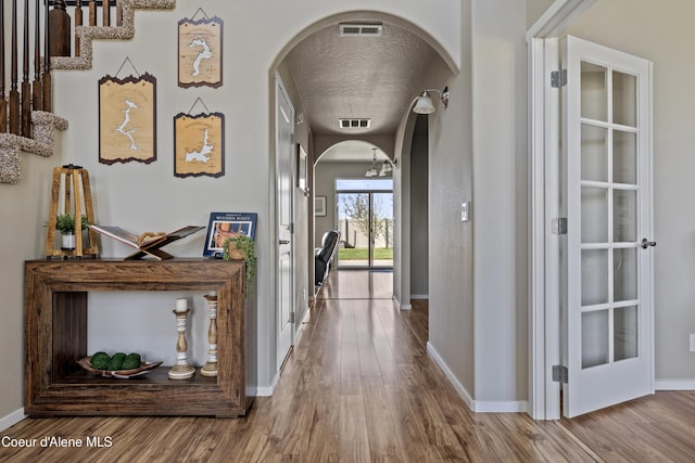 9362 N Prince William Loop, Hayden, ID 83835 - hallway featuring arched walkways, wood finished floors, a textured ceiling, and baseboards