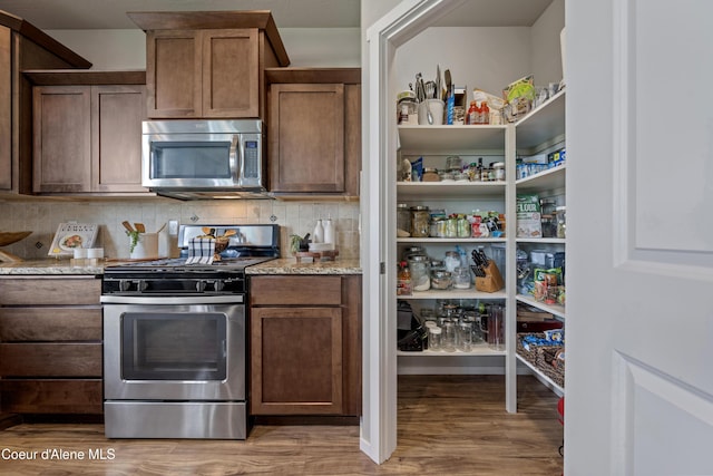 9362 N Prince William Loop, Hayden, ID 83835 - kitchen featuring stainless steel appliances, light wood-style floors, light stone countertops, decorative backsplash, and open shelves