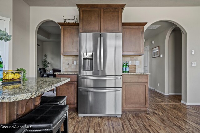 9362 N Prince William Loop, Hayden, ID 83835 - kitchen with stainless steel fridge, arched walkways, dark wood finished floors, and light stone countertops