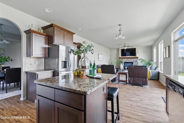 9362 N Prince William Loop, Hayden, ID 83835 - kitchen with stainless steel appliances, a chandelier, a fireplace, light stone countertops, and light wood-style floors