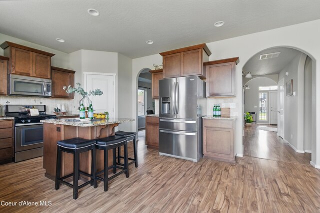 9362 N Prince William Loop, Hayden, ID 83835 - kitchen featuring stainless steel appliances, light wood-style flooring, decorative backsplash, arched walkways, and recessed lighting