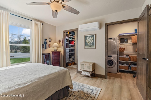 17 Hitchcock Dr, Dover, ID 83825 - bedroom with stacked washing machine and dryer, a wall mounted air conditioner, light wood-style flooring, baseboards, and a ceiling fan