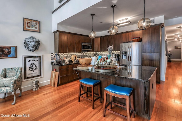 412 Sandpoint Ave Unit 332, Sandpoint, ID 83864 - kitchen with dark brown cabinetry, backsplash, appliances with stainless steel finishes, light wood-type flooring, and a breakfast bar