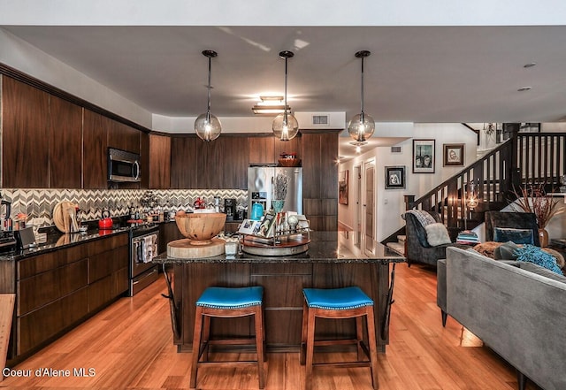 412 Sandpoint Ave Unit 332, Sandpoint, ID 83864 - kitchen featuring dark brown cabinets, light wood-style floors, open floor plan, a kitchen bar, and appliances with stainless steel finishes