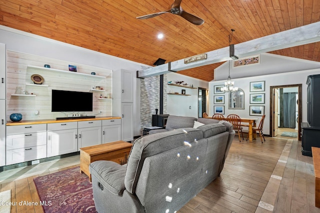 living area featuring a wood stove, wood ceiling, lofted ceiling with beams, light wood-style flooring, and ceiling fan with notable chandelier