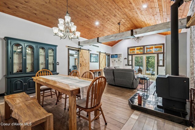 dining room with wood ceiling, a wood stove, hardwood / wood-style flooring, a barn door, and an inviting chandelier