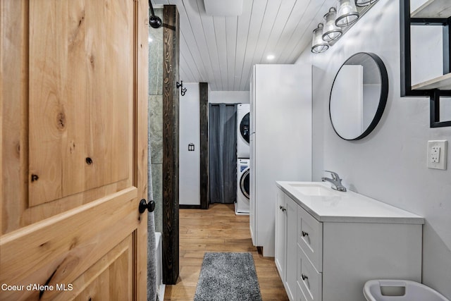 bathroom featuring stacked washing maching and dryer, vanity, wooden ceiling, and wood finished floors