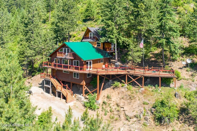 rear view of house featuring a wooded view, stairs, and a deck