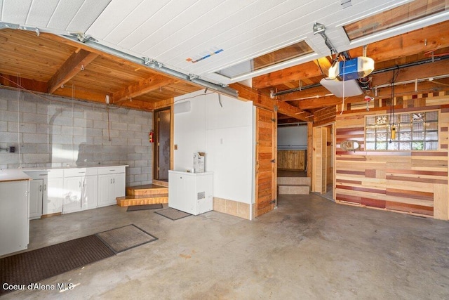 garage with wooden walls, concrete block wall, and a garage door opener