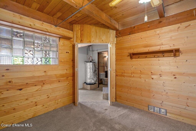 unfurnished room featuring wooden walls, wooden ceiling, water heater, and visible vents
