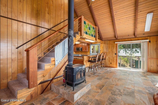 interior space with stone tile floors, a wood stove, wood ceiling, and wooden walls