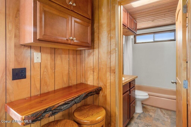 full bath featuring vanity, wood walls, toilet, wooden ceiling, and stone finish flooring