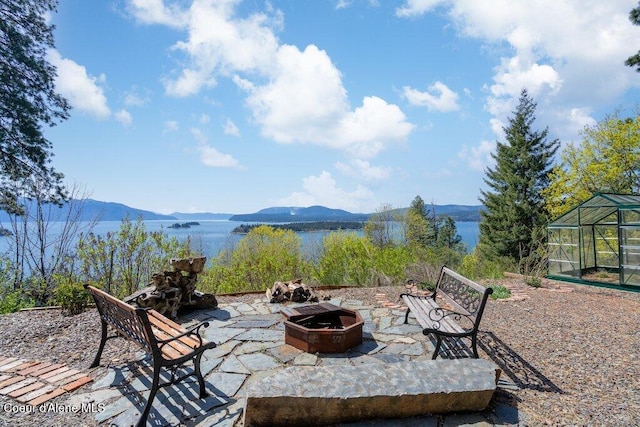 view of patio / terrace featuring a greenhouse, a mountain view, and an outdoor fire pit
