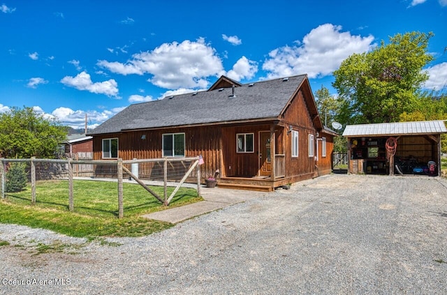 back of house with fence and gravel driveway