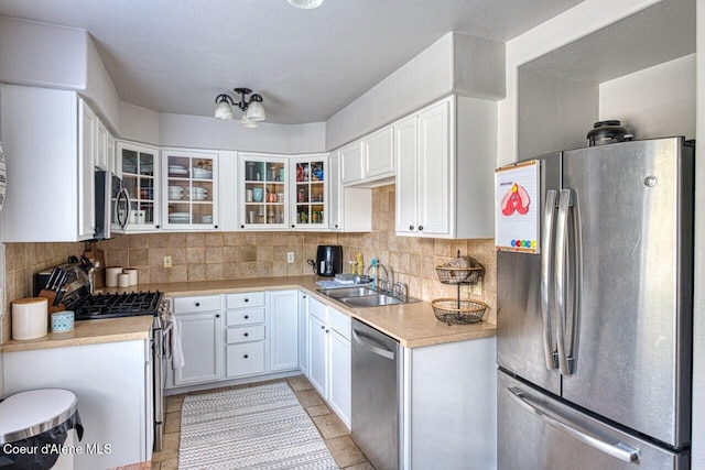 kitchen featuring stainless steel appliances, a sink, tasteful backsplash, and light countertops
