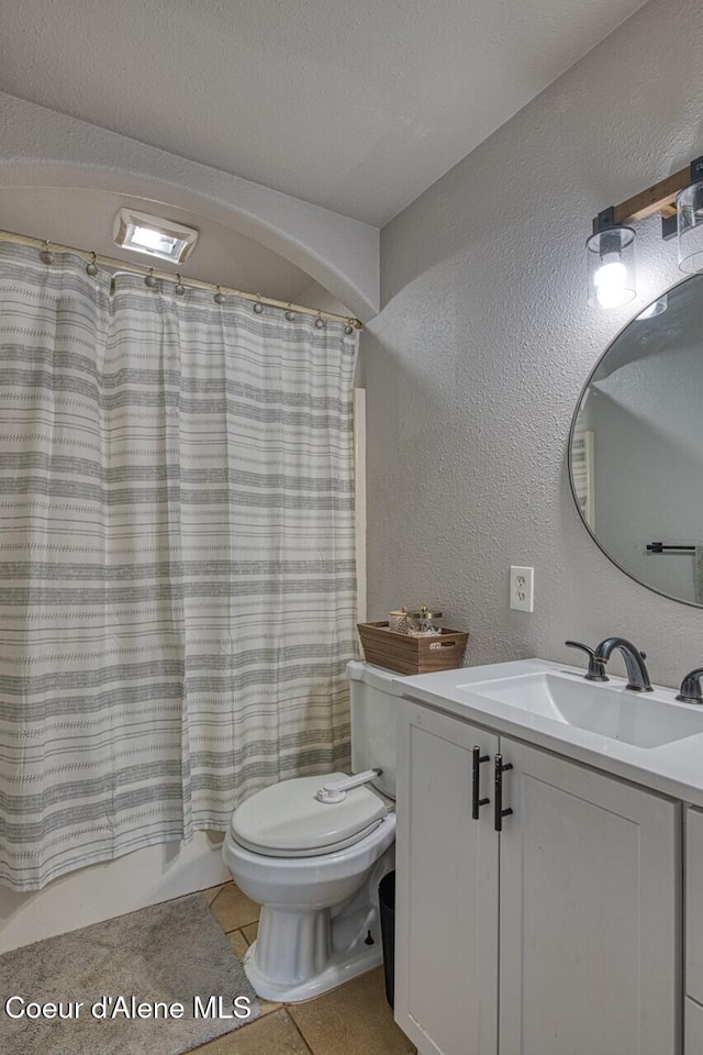full bath featuring a textured wall, toilet, vanity, tile patterned floors, and shower / tub combo