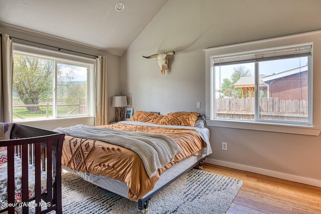 bedroom featuring vaulted ceiling, light wood-type flooring, and baseboards