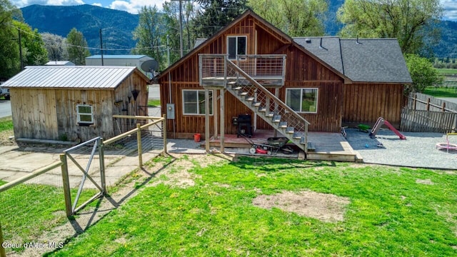 back of house with a deck with mountain view, stairway, an outbuilding, and a shingled roof