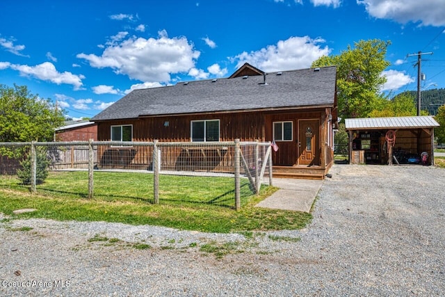 back of property with a detached carport, roof with shingles, board and batten siding, and driveway