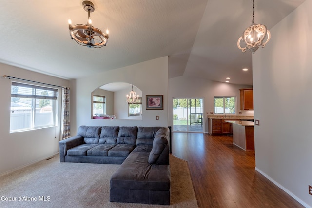 living room featuring baseboards, lofted ceiling, and a notable chandelier