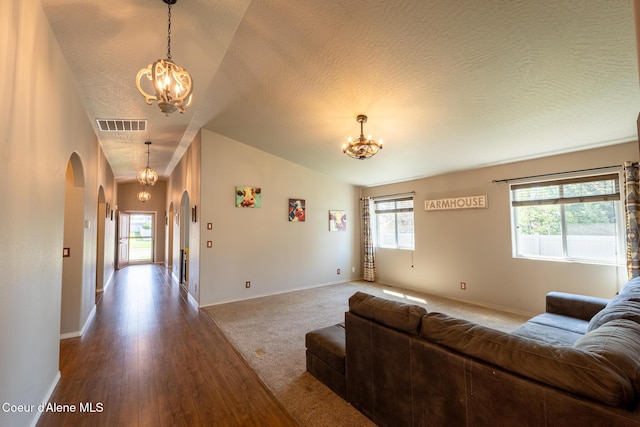 living area featuring an inviting chandelier, arched walkways, vaulted ceiling, and visible vents