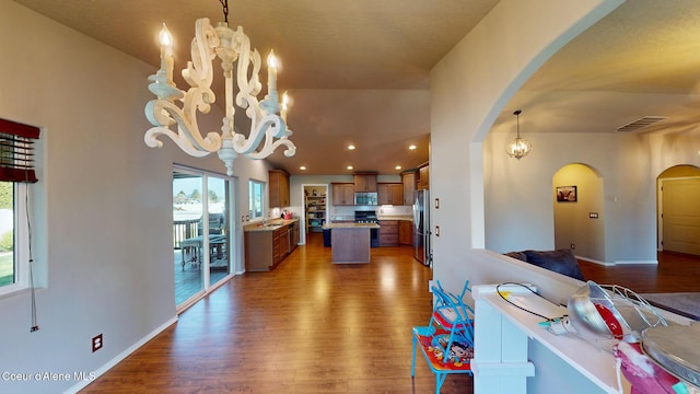 kitchen with an inviting chandelier, arched walkways, appliances with stainless steel finishes, and open floor plan
