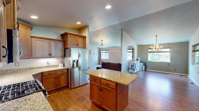 kitchen with a textured ceiling, a chandelier, wood finished floors, open floor plan, and stainless steel appliances