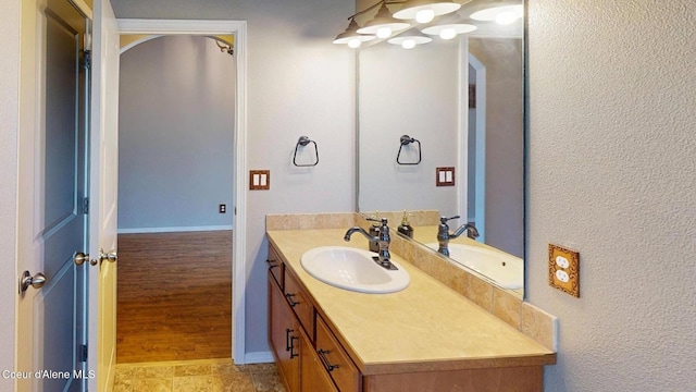 bathroom with vanity, baseboards, and a textured wall
