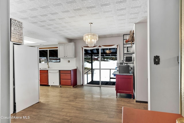 19856 B St Joe River Rd, Calder, ID 83808 - kitchen with white appliances, a notable chandelier, wood finished floors, and an ornate ceiling