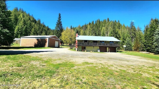 19856 B St Joe River Rd, Calder, ID 83808 - view of front facade with a wooden deck, an outdoor structure, a front yard, and a forest view