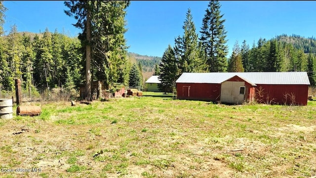 19856 B St Joe River Rd, Calder, ID 83808 - view of yard featuring an outdoor structure, an outbuilding, and a forest view