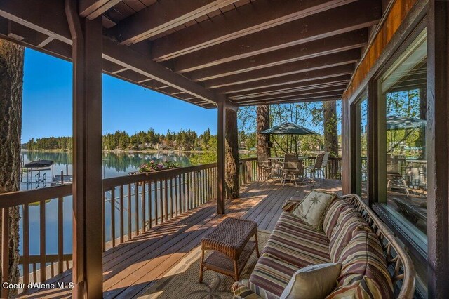 wooden terrace featuring a water view and outdoor dining space