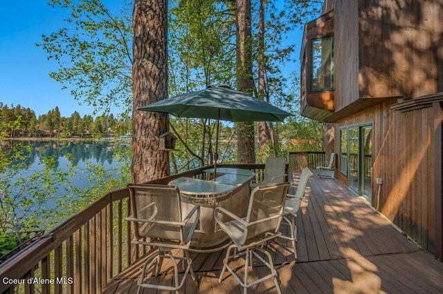 wooden terrace featuring a water view and outdoor dining space
